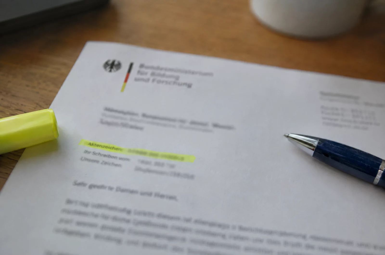 Nahaufnahme eines Behördenschreibens, auf dem die Zeile mit dem Aktenzeichen mit gelbem Textmarker hervorgehoben ist.