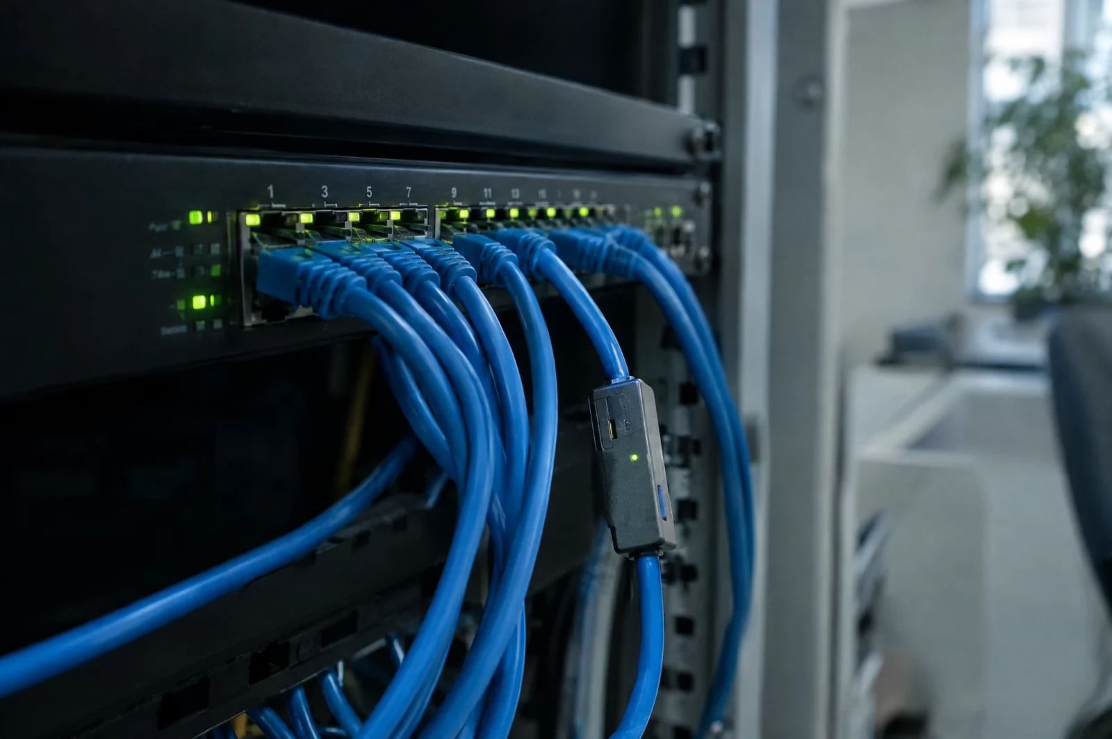 Ausspähen von Daten - § 202a StGB Netzwerk-Switch mit vielen Kabeln und grünen Status-LEDs, Sinnbild für das Abfangen von Daten auf dem Übertragungsweg nach § 202b StGB.