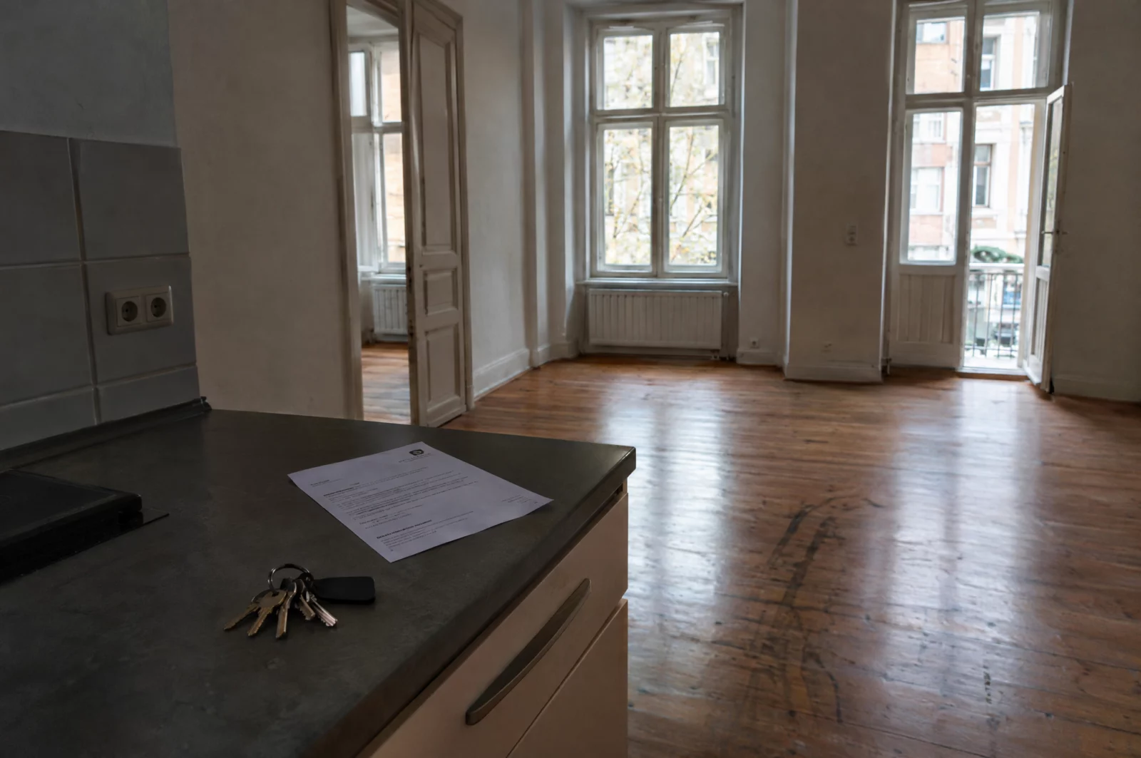Betrug - § 263 StGB In einer leeren Altbauwohnung liegen Schlüssel und eine Mahnung auf der Küchenzeile – Sinnbild für den Vorwurf des Einmietbetrugs.