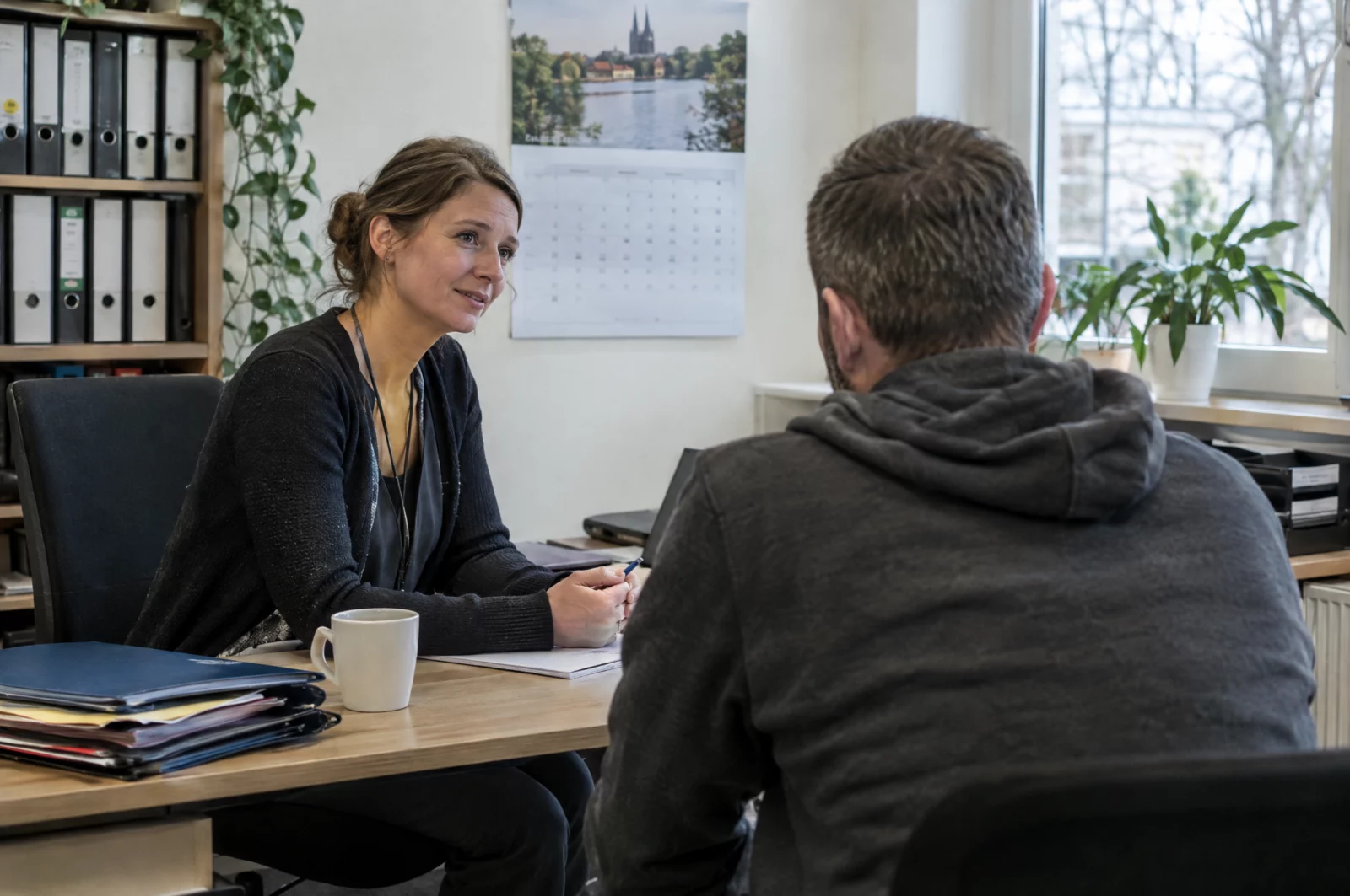 Bewährung Bewährungshelferin im Gespräch mit einem Probanden in einem hellen Büro, regelmäßige Termine gehören zu den Pflichten der Bewährungszeit.