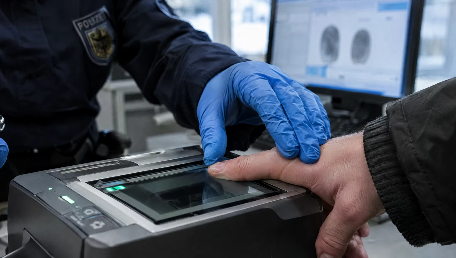Ein Finger wird bei der Polizei auf einen digitalen Fingerabdruckscanner gedrückt, Kern der erkennungsdienstlichen Behandlung.