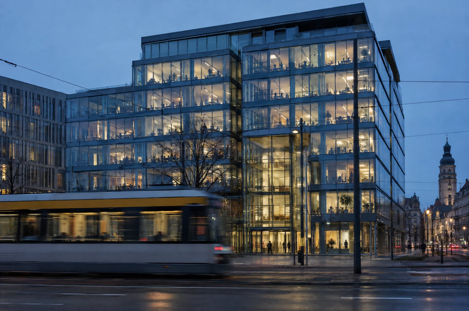 Kreditbetrug - § 265b StGB Beleuchtetes Bürogebäude einer Bank zur blauen Stunde mit vorbeifahrender Straßenbahn, Kulisse für Vorwürfe des Kreditbetrugs.