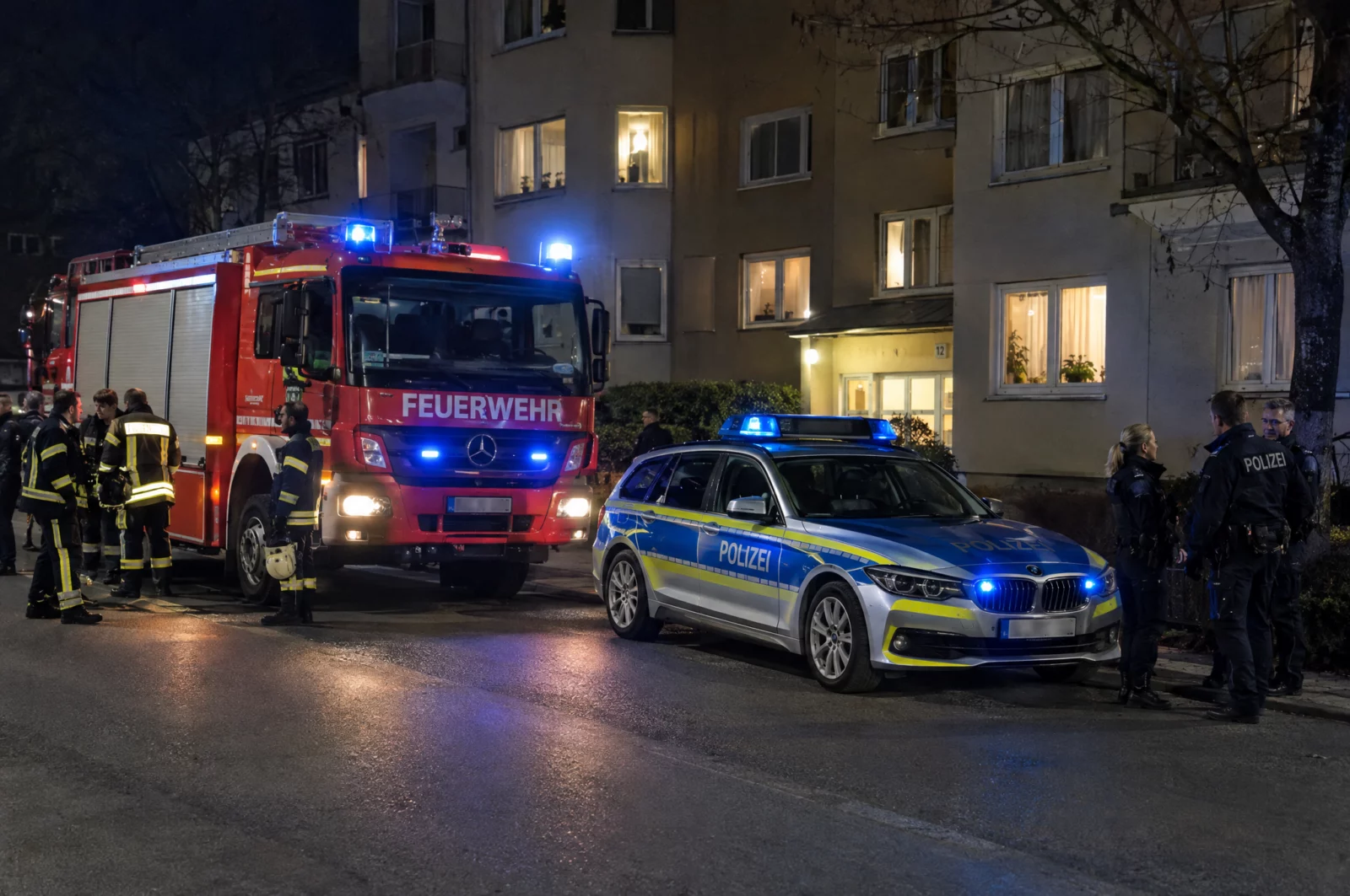 Feuerwehr und Polizei stehen nachts mit Blaulicht vor einem Wohnhaus, ohne dass ein Notfall vorliegt – Folge eines Notrufmissbrauchs.