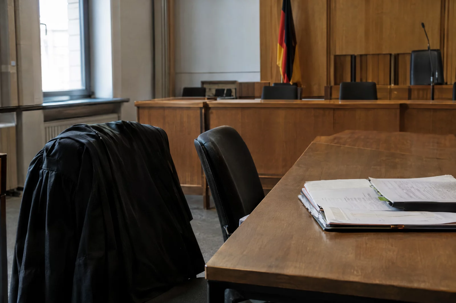 Öffentlichkeit im Verfahren Leerer Platz des Angeklagten neben der Verteidigerbank mit Robe und Akte, Sinnbild für den Ausschluss nach § 247 StPO.