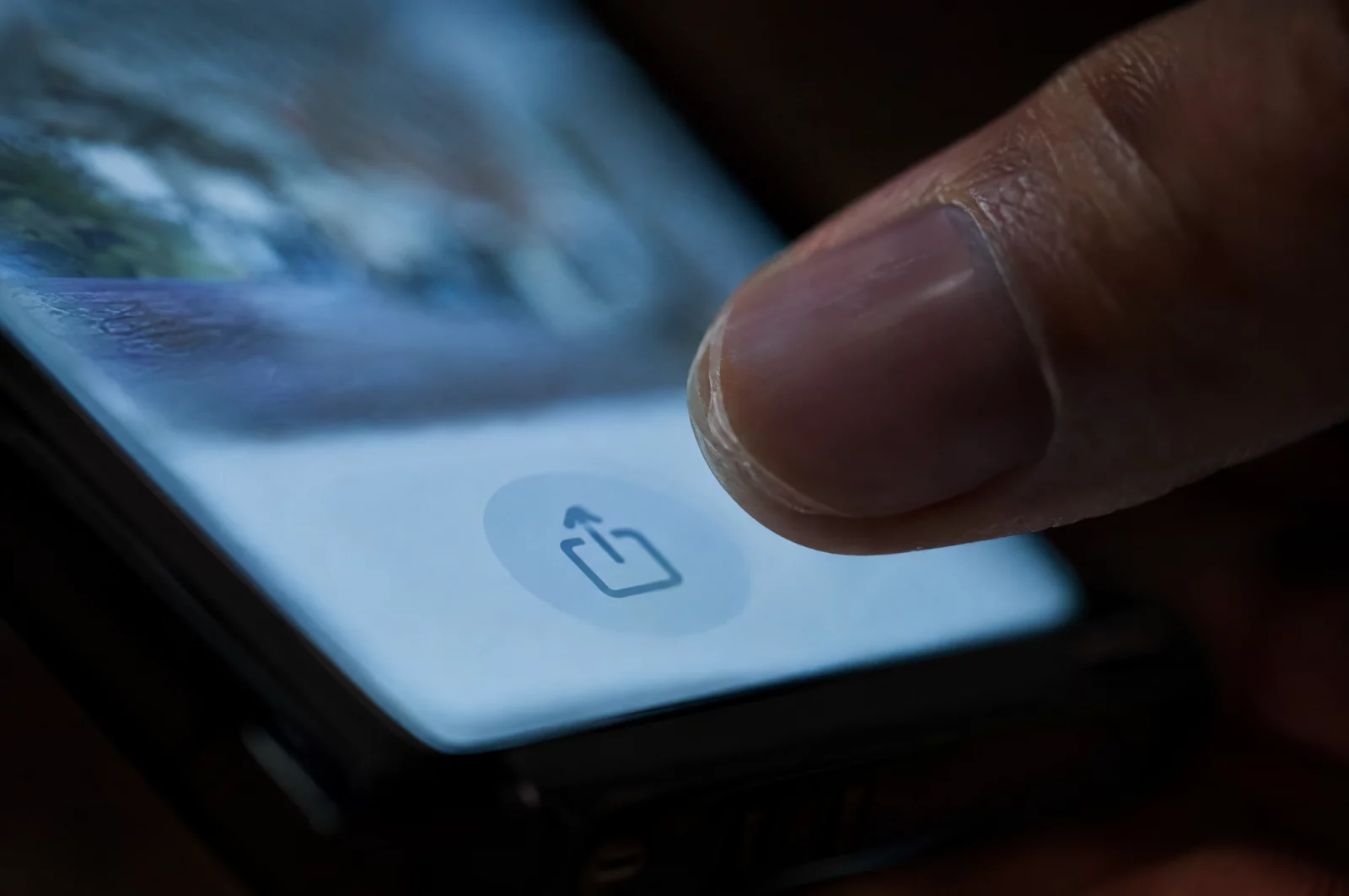 Daumen schwebt über der Teilen-Funktion eines Smartphones, der Moment, in dem das Weiterleiten intimer Aufnahmen strafbar wird.