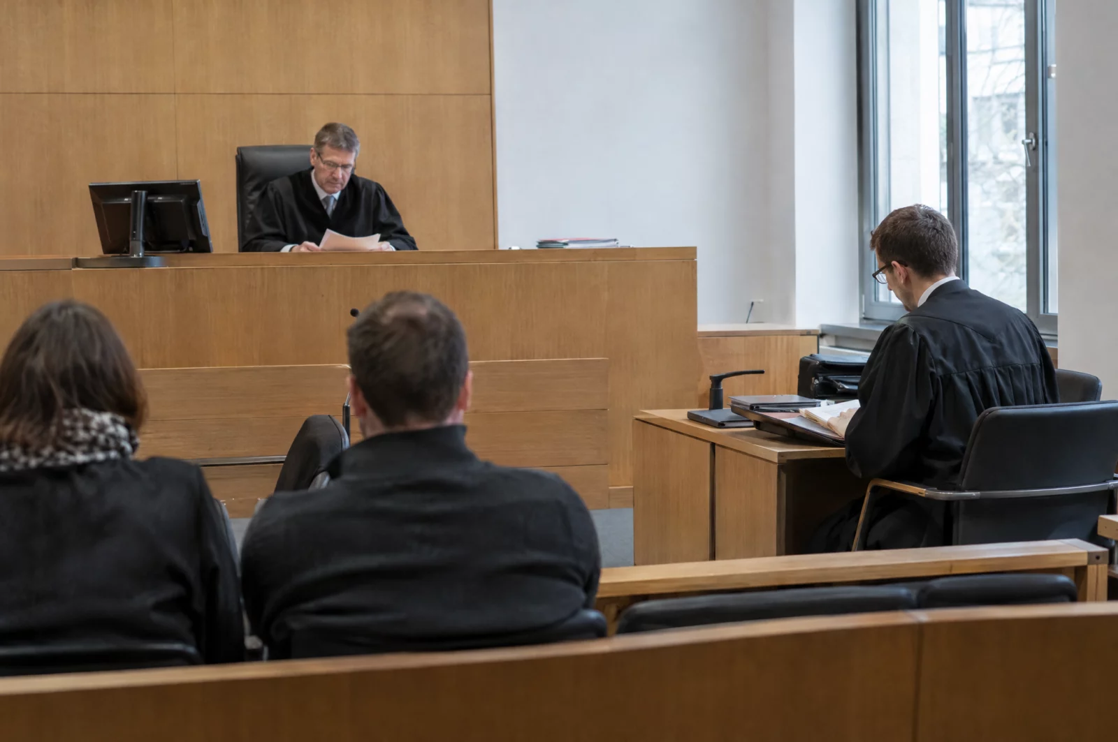 Ein Einzelrichter liest an der Richterbank eines Amtsgerichts in den Akten, seitlich sitzt der Verteidiger in Robe.