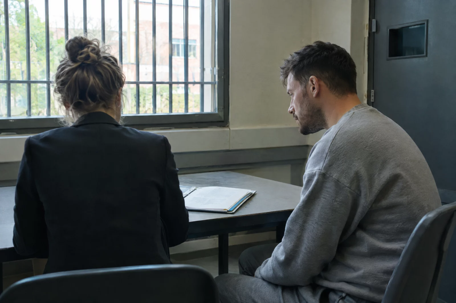 Verteidiger bespricht mit seinem Mandanten im Besuchsraum der Untersuchungshaft die Ermittlungsakte zum Totschlagsvorwurf.