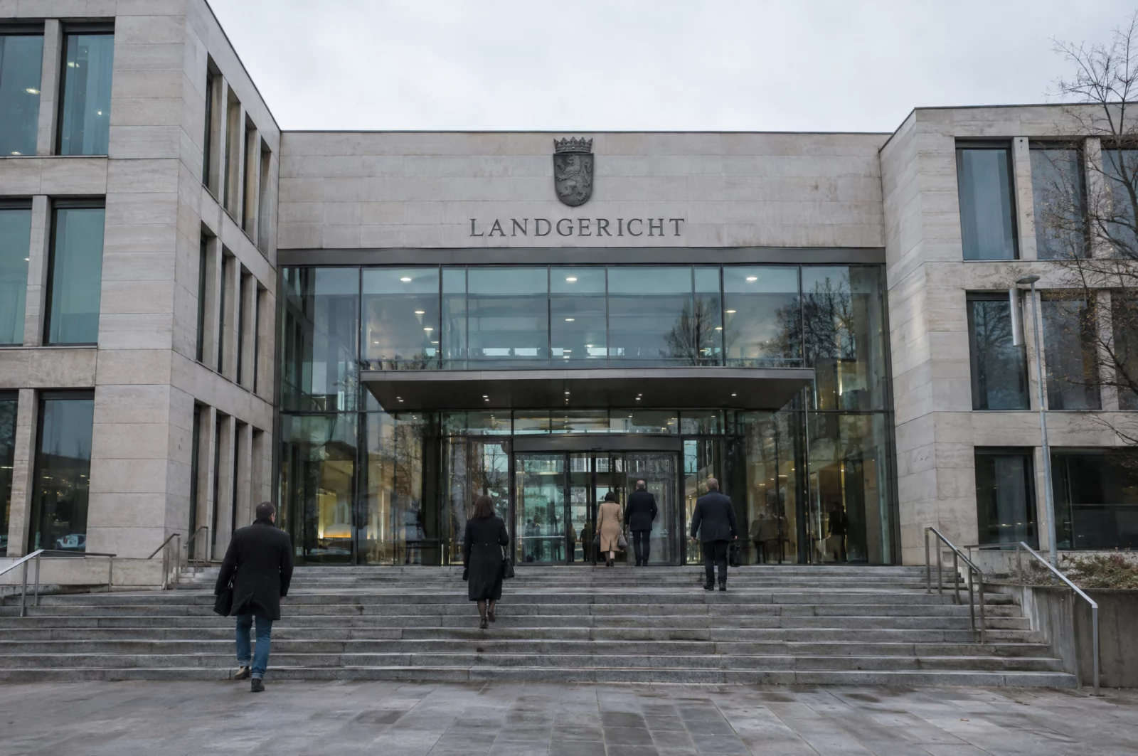 Menschen betreten ein modernes Justizgebäude aus Stein und Glas, in dem auch Anklagen wegen Volksverhetzung verhandelt werden.