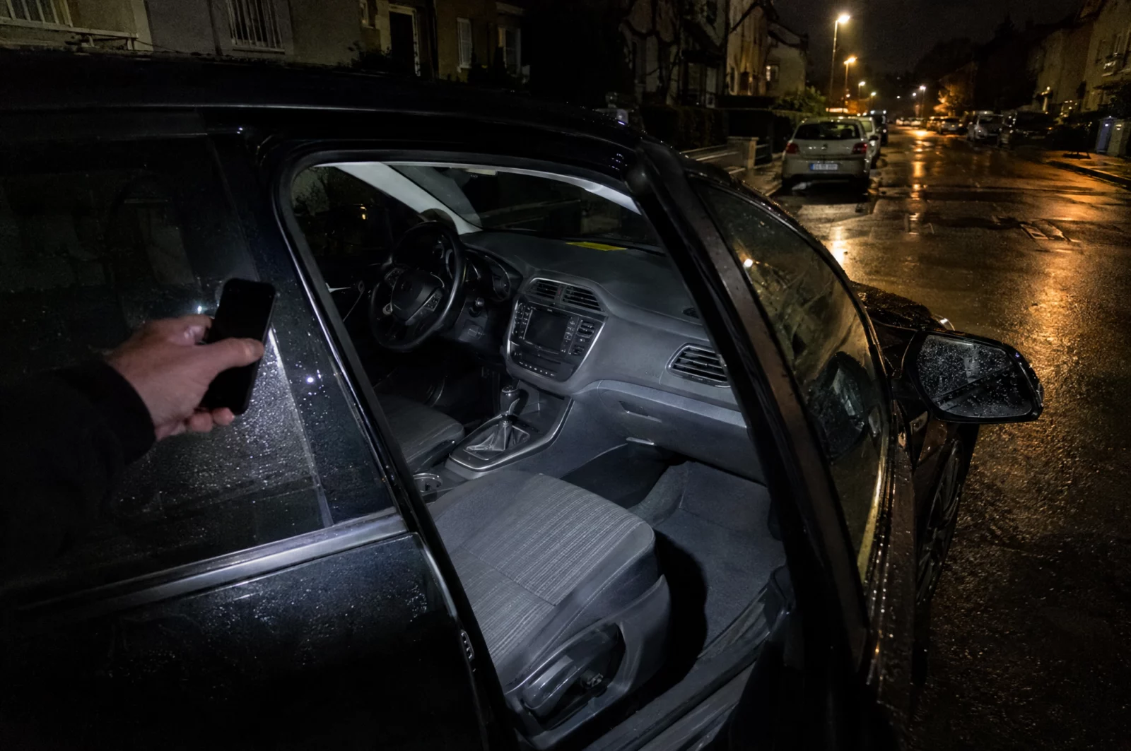 Eine Taschenlampe leuchtet nachts in ein Auto mit unbeschädigter Scheibe – Indiz für einen nur vorgetäuschten Aufbruch.
